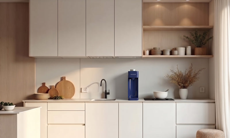 Purificador de agua Nahua azul sobre el mesón de una cocina de departamento moderna