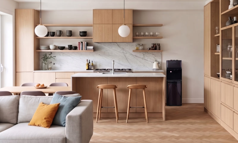 Dispensador de agua tipo pedestal junto a una cocina moderna de madera clara